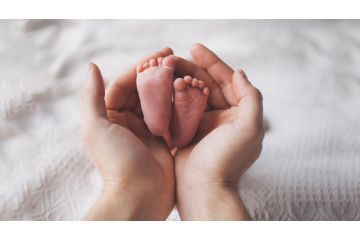 L'immagine mostra le mani di una mamma disposte a coppa che tengono i piedini di un neonato